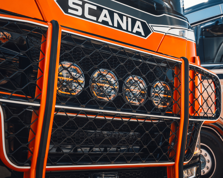 Detailansicht eines orangefarbenen LKW mit Schutzgitter.